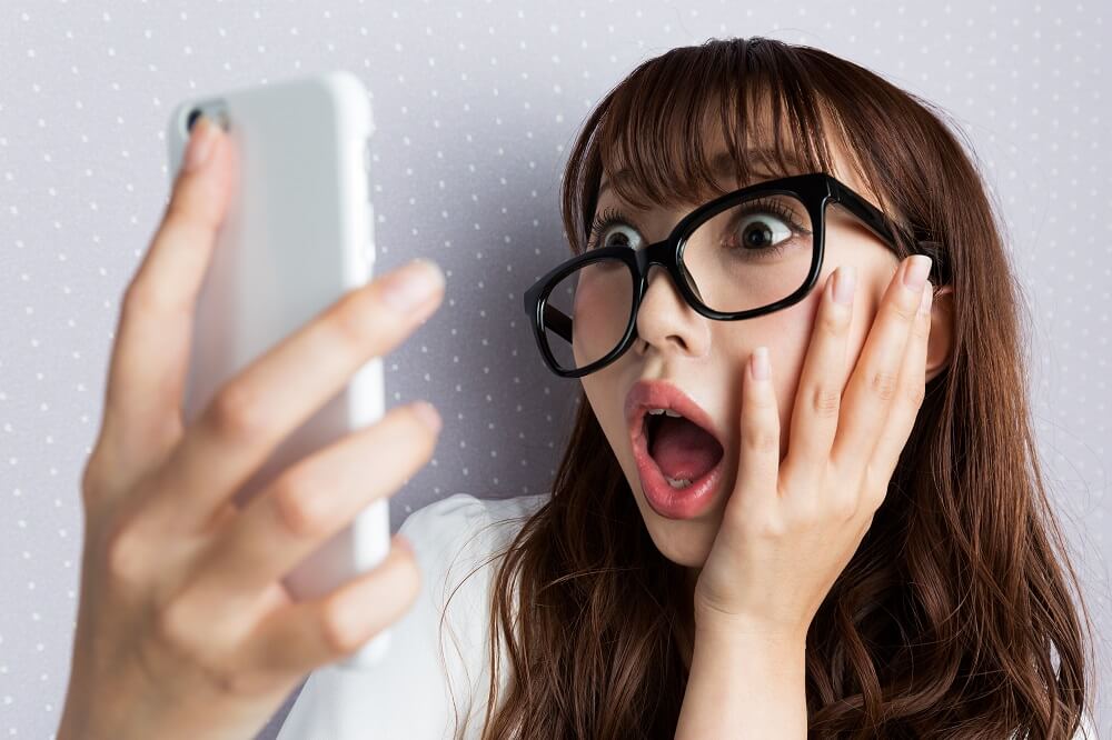 Super surprised woman face up looking at smartphone